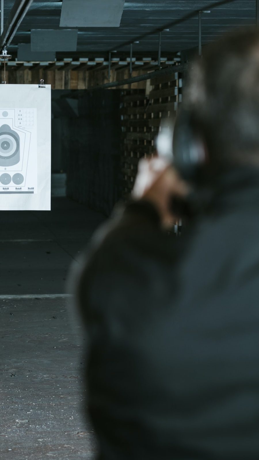 rear-view-of-man-aiming-gun-at-target-in-shooting-range-1.jpg